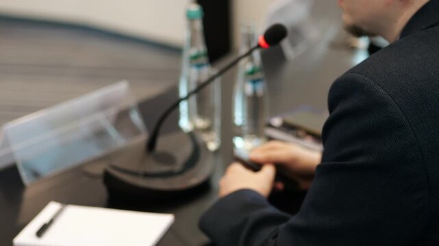 Businessman holding presentation clicker near microphone at conference table concept of business meeting presentation control and public speaking preparation.