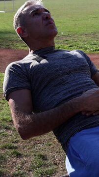 54-Year-Old Fit Man in Excellent Physical Condition Doing Crunches on Parallel Bars. Athletic Middle Aged Man Doing Sit-ups. Series Track Code: Fit-Mature-Man-54-Outdoor-Fitness-Series-2024