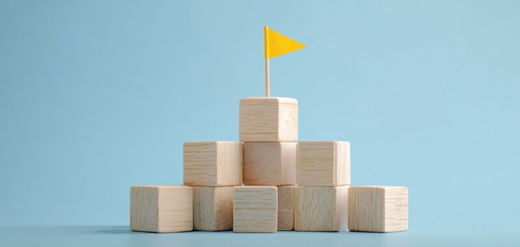 The wooden block pyramid topped with a yellow flag symbolizing achievement and success