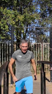 Strong Senior Male Doing Parallel Bar Dips - Calisthenics Park - Street Workout. Series Track Code: Fit-Mature-Man-54-Outdoor-Fitness-Series-2024