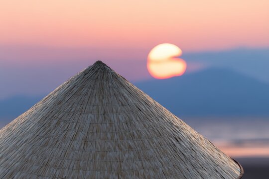 茅葺き屋根を背景にした夕日の景色