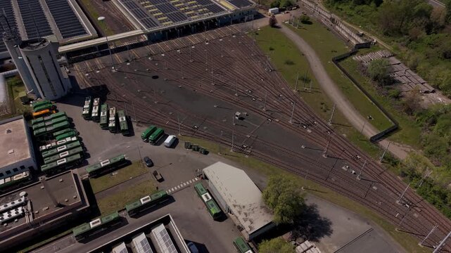 Industrial Rail Yard Logistics: An aerial view captures a sprawling industrial rail yard, featuring multiple tracks, parked train cars, and various industrial buildings.