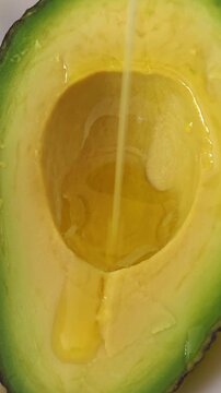 vegetable oil drop on cut avocado ready for use. vertical video.