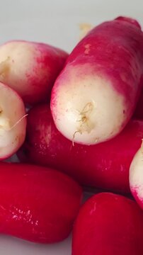 Fresh radishes on a flat surface. vertical video.