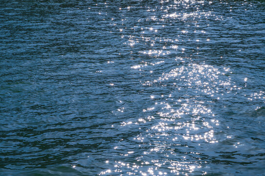 Sparkling sunlight dances on the deep blue rippling water surface