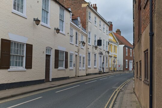 A quiet, narrow street is lined with traditional, light-colored buildings featuring shuttered windows in Beverley - Yorkshire - Great Britain