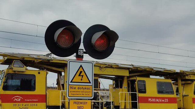 Przejazd kolejowy z migającymi czerwonymi światłami ostrzegawczymi i przejeżdżającym pojazdem.