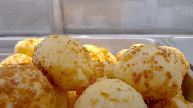 Closeup of cheese puffs steaming in the window of a Brazilian bakery.