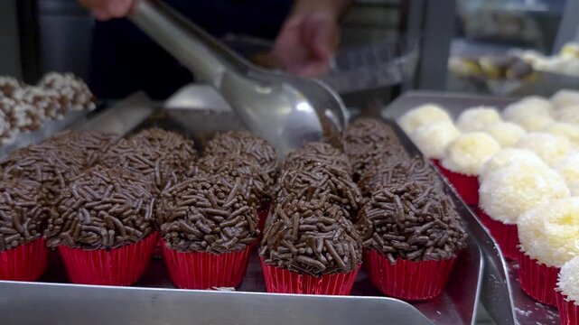 Server taking a Brazilian fudge ball and placing it in a container for takeout.