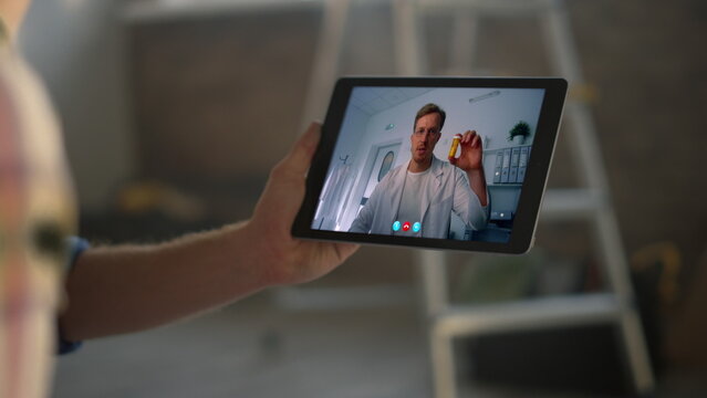 Remote doctor talking pad screen at clinic closeup. Patient hands holding tablet