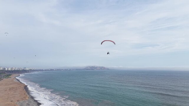 Aerial view of powered paraglider flying over the ocean along the coast of Lima Peru
