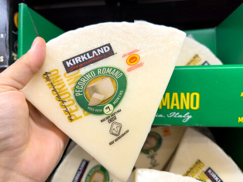 Hand holding large triangular piece of pecorino romano cheese made