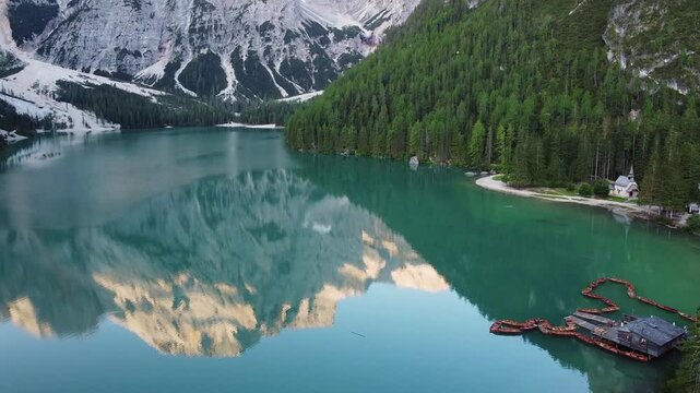 Scenic alpine lake with turquoise water, mountain reflections, forest shoreline, and small chapel