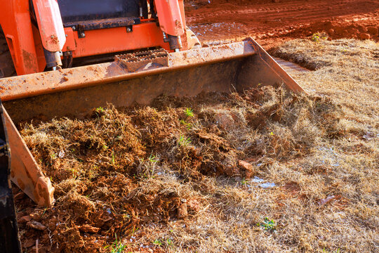 Heavy machinery works to move dirt debris in rural location during landscaping work with soil grass land clearing,
