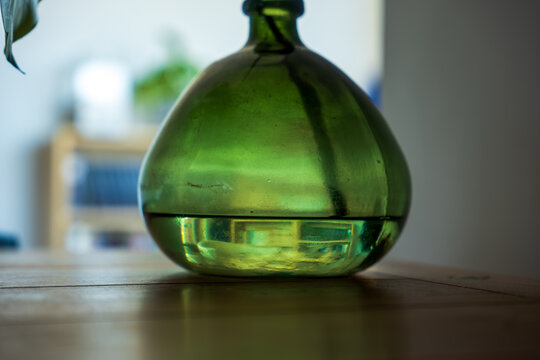 Green glass bottle base on wooden table in Madeira home interior