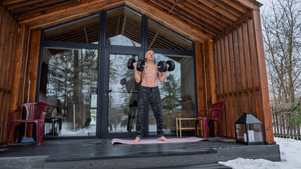Fototapeta premium Dumbbell gymnastics on the porch of the house.