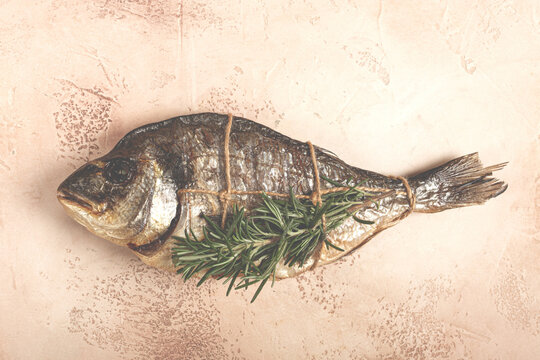 hot smoked dorado fish, with a sprig of rosemary, tied with a rope, on the table, top view, smoked fish, close-up, no people,