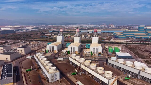 CCGT power plant featuring gas turbine halls, heat recovery steam generators (HRSG), mechanical draft cooling towers, high-voltage switchyard, and red-white striped exhaust stacks