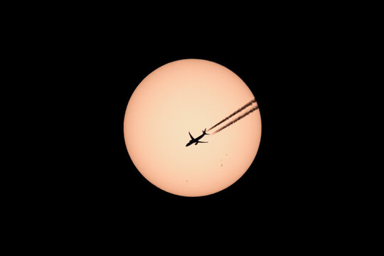 Silhouette of twin engined passenger jet plane  passing across the sun en route from Paris to Alicante