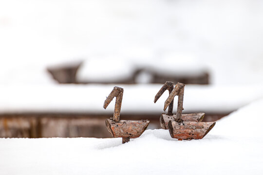Miniature wooden bird figurines inspired by Korean sotdae standing on snow in a quiet winter scen
