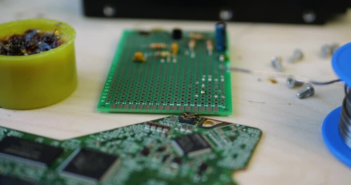 Tech workshop features circuit boards and tools. Craftsman repairs electronic devices with precision. Focus on intricate details of technology. Innovation drives progress in electronics.