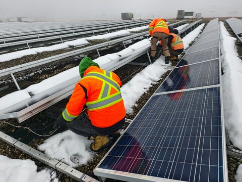Engineers install and repair solar panels on a roof during winter. The concept of alternative, renewable energy sources, clean, solar, and green energy.