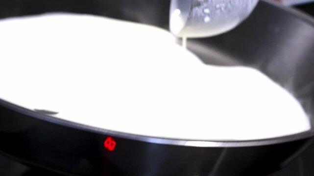 Pouring creamy batter into a heated pan, bubbles forming as it cooks, showcasing the transformation of liquid into a fluffy texture in a kitchen setting