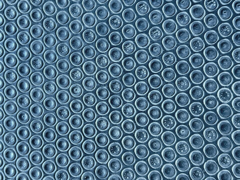 Close up mosaic rubber in round circular pattern in dark color. Suitable for flooring, wall, gymnasium, fitness, and automotive carpet base. Seamless background texture.