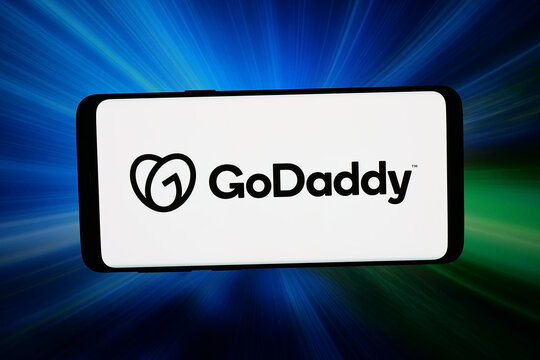 Stuttgart, Germany - 03-31-2026: In this photo illustration, the logo of US web hosting company GoDaddy Inc. is displayed on a smartphone in front of abstract background on computer screen.