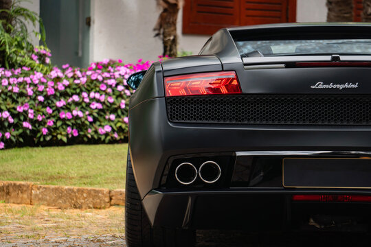 Matte black Lamborghini Gallardo rear left taillight and exhaust, Luxury sports car details parked on cobblestone driveway
