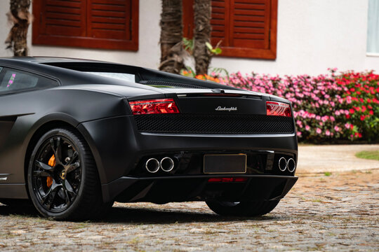Matte black Lamborghini Gallardo rear quarter outdoors, Luxury sports car on stone driveway near mansion