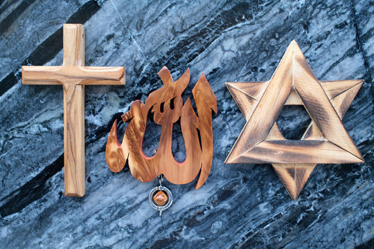 Three Abrahamic religion. Interreligious harmony shown through wood-carved cross, Allah pendant, and Star of David.