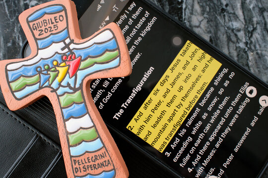 Jubilee 2025 cross beside smartphone displaying Bible app with Transfiguration passage highlighted.