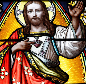 Saint Germain church.  Christ with Sacred Heart depicted in stained glass, red robes, raising hand in blessing. Duingt. France.