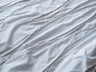 Obraz premium White fabric with soft creases and deep folds forming an abstract bedding background, gentle play of light and shadow on smooth cotton surface for cozy, relaxed bedroom scenes