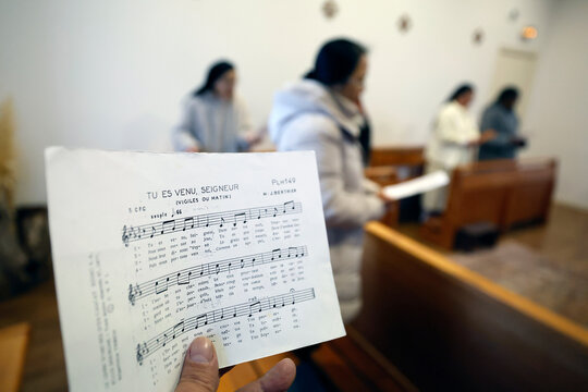  Dominican convent of Bor. Hand holds a sheet of music titled Tu es venu, Seigneur during a monastic prayer service. Bor et Bar. France.