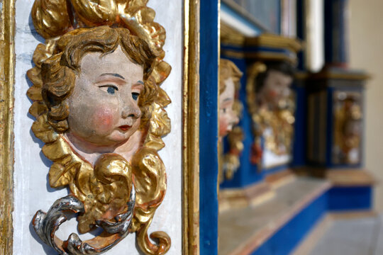 Baroque chapel of La Gruvaz after restoration.  Carved angel head emerges from ornate golden frame of the restored chapel retable.  Saint Gervais.  France.