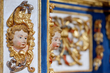 Fototapeta premium Baroque chapel of La Gruvaz after restoration. Carved angel head emerges from ornate golden frame of the restored chapel retable. Saint Gervais. France.
