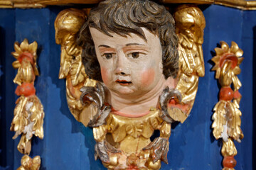 Fototapeta premium Baroque chapel of La Gruvaz after restoration. Carved angel head emerges from ornate golden frame of the chapel retable. Saint Gervais. France.