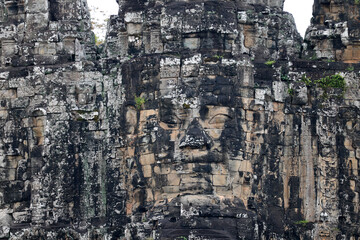 Naklejka premium Weathered statue of serene and smiling stone face on Bayon temple, in Angkor Thom. Siem Reap. Cambodia.