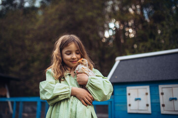 Child gently holding baby chicken, playing in garden during spring. © Halfpoint