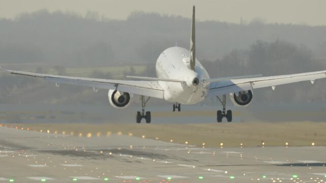 Passenger airplane executes a smooth landing on a busy airport runway in early morning light