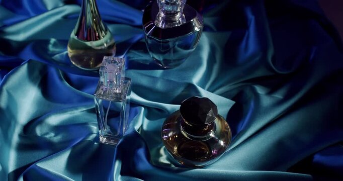 Aesthetic arrangement of elegant perfume bottles displayed on a luxurious blue satin fabric, exuding sophistication and style. Elegant Perfume Bottles on Luxurious Blue Satin Fabric Background