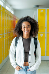 Student standing in school locker room with colorful lockers.