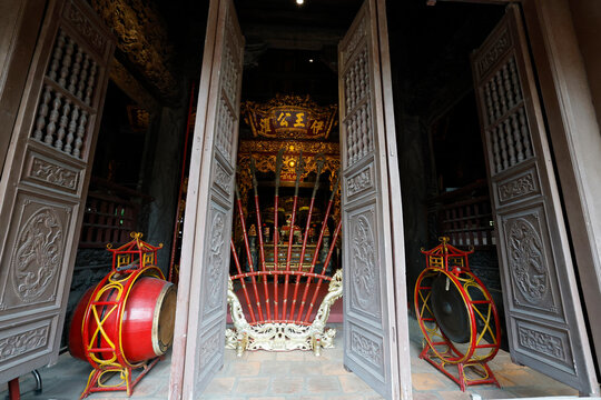 Communal house dedicated to national hero Ngo Quyen.Red lacquered ceremonial pole weapons fan out before a richly decorated temple. Haiphong. Vietnam.