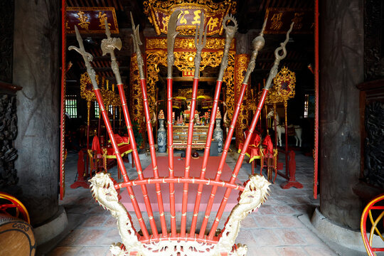 Communal house dedicated to national hero Ngo Quyen.Red lacquered ceremonial pole weapons fan out before a richly decorated temple. Haiphong. Vietnam.