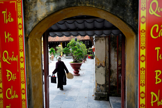 Phuc Lam Du Pagoda. Elderly Vietnamese woman in dark ao dai entering.  Haiphong. Vietnam.
