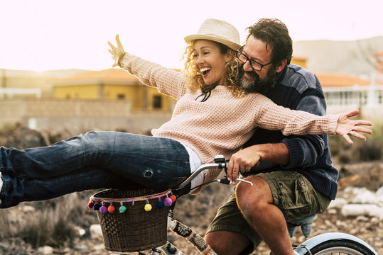 Happy couple riding a bicycle together, playful summer romance and joyful outdoor adventure