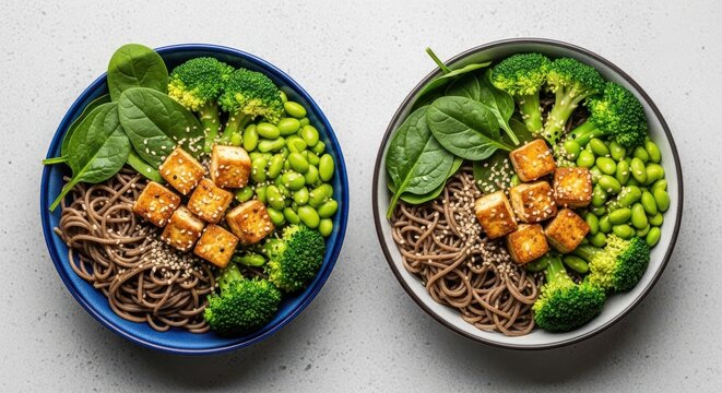 Two bowls of healthy vegan soba noodle salad with tofu, edamame, broccoli, and spinach, top view