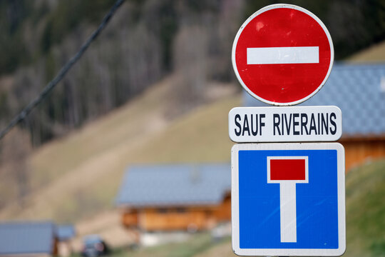 Three stacked French road signs prohibit entry except for local residents near a mountain village chalet.  Saint Gervais.  France.